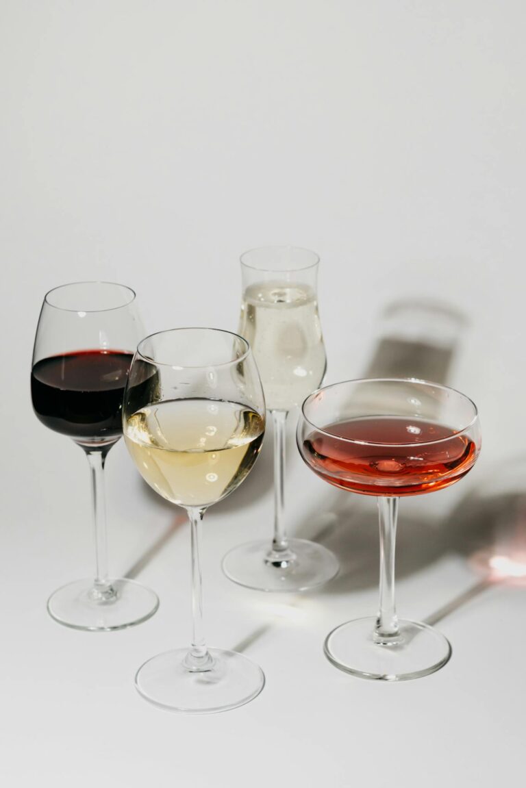 An elegant still life of various wine glasses showcasing different types of wines on a minimalist surface.